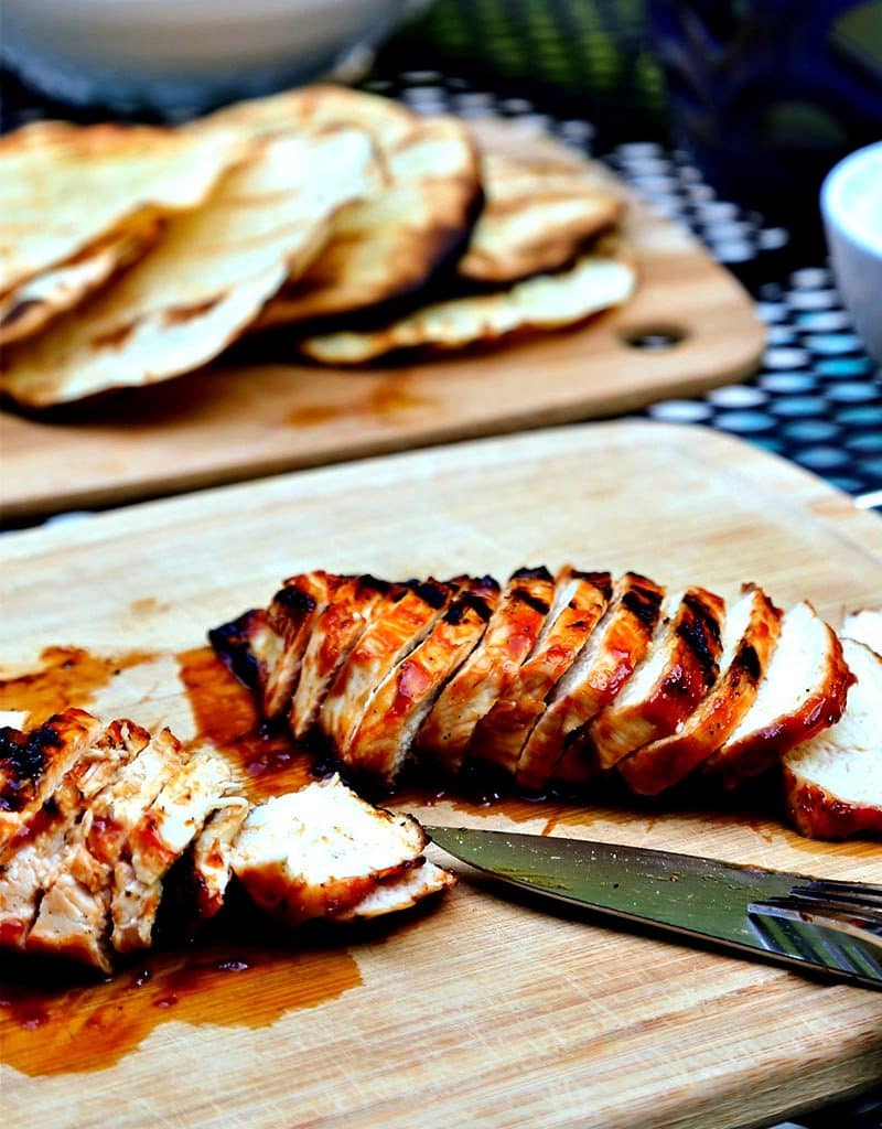 Slices of chicken sitting on top of a wooden cutting board, with BBQ Chicken Tostadas