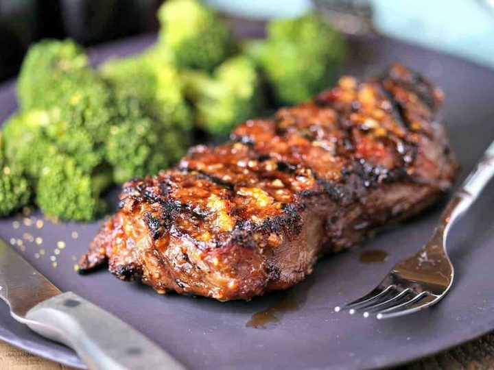 A close up of a plate of Mongolian Glazed Grilled Steak with a fork and knife