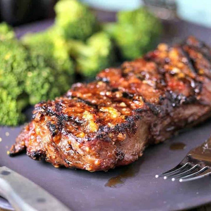 A close up of a plate of Mongolian Glazed Grilled Steak with a fork and knife