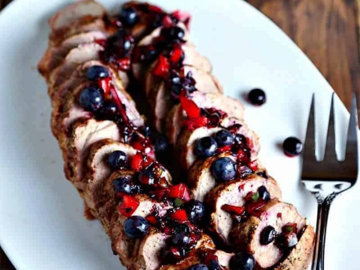 A plate of Grilled Pork Tenderloin with Blueberry Salsa and a meat fork