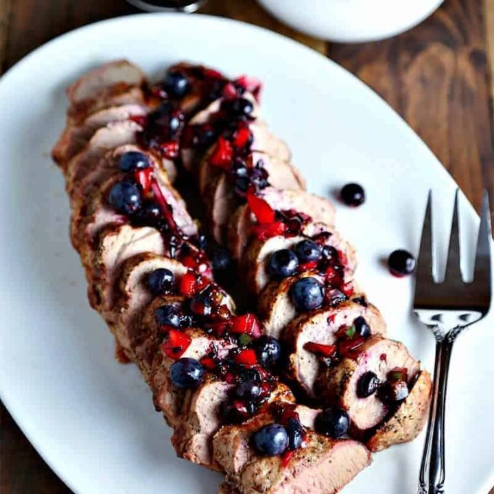 A plate of Grilled Pork Tenderloin with Blueberry Salsa and a meat fork