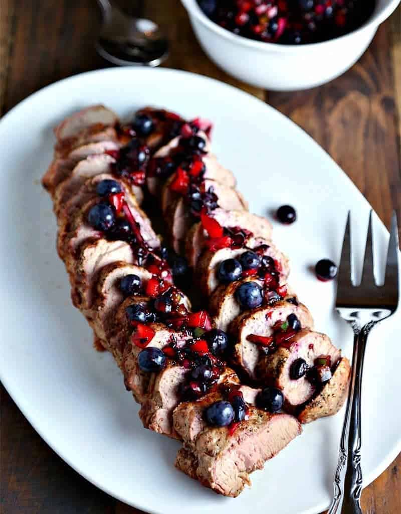 A plate of Grilled Pork Tenderloin with Blueberry Salsa and a meat fork