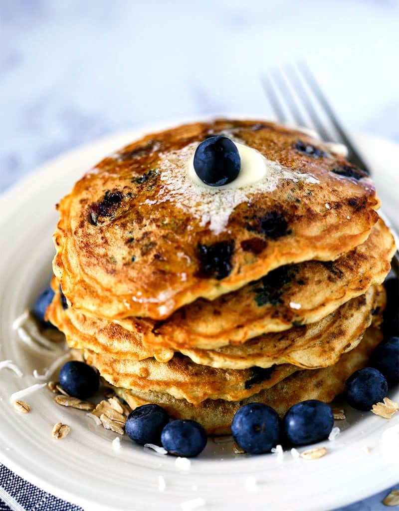 A stack of blueberry coconut oatmeal pancakes on a plate