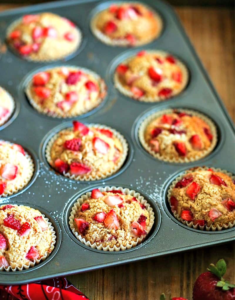 a muffin pan of strawberry muffins on a table