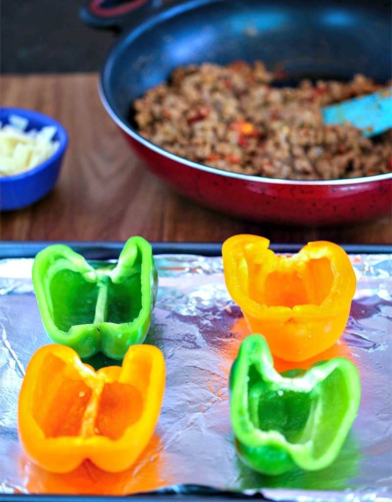 Green and yellow bell peppers halves on a baking sheet