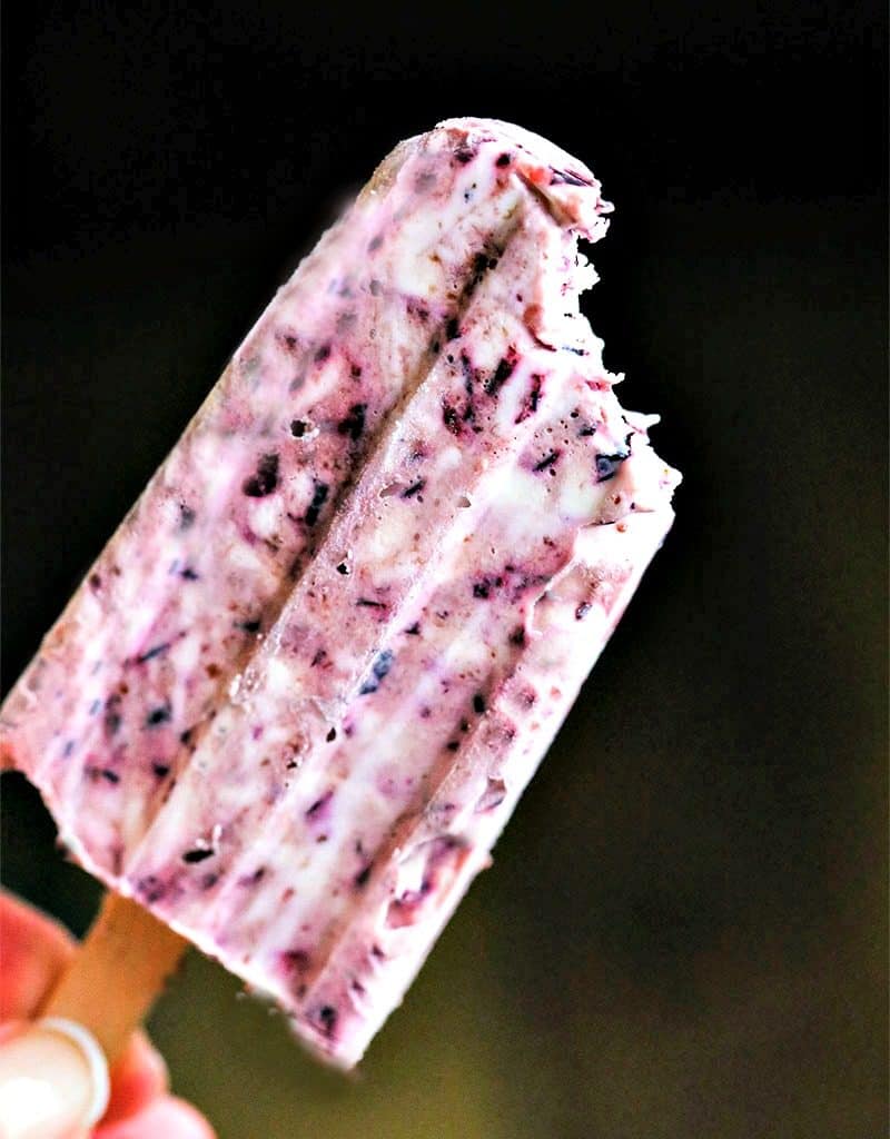 A blueberry cheesecake popsicle with a bite taken out of it