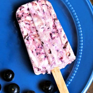 A blueberry cheesecake popsicle on a blue plate