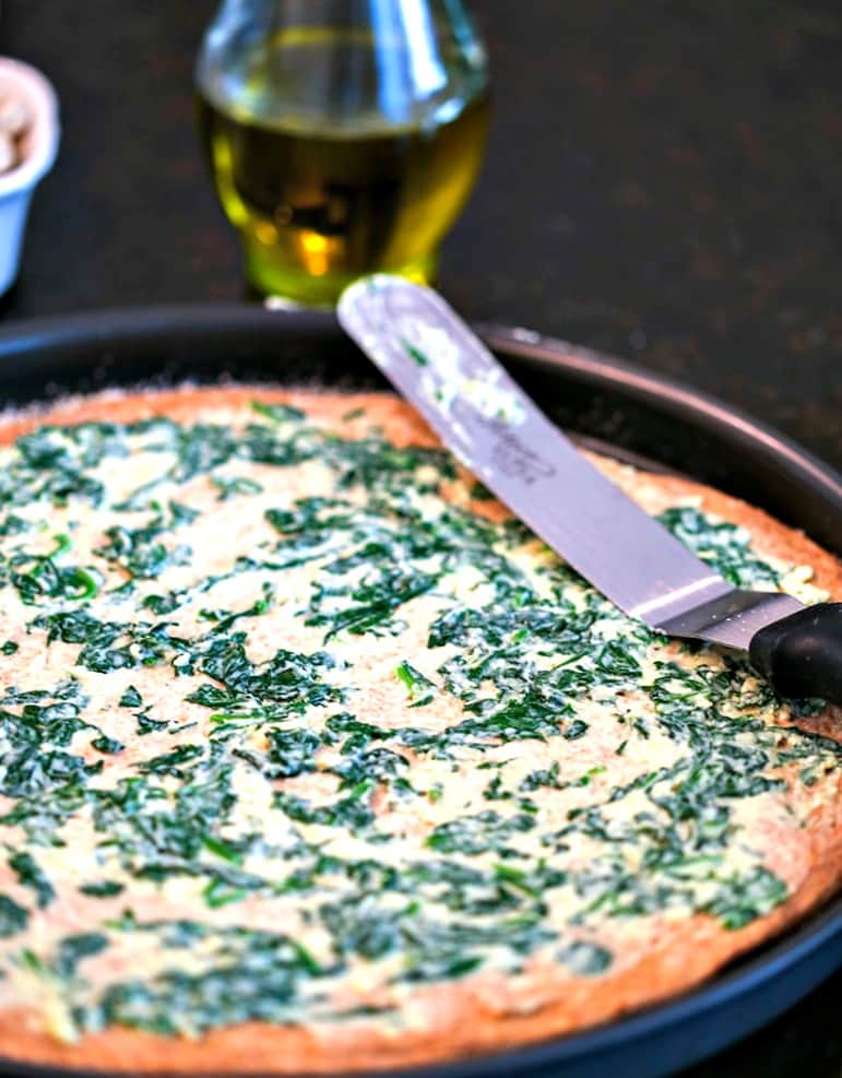 A pizza crust spread with spinach mixture