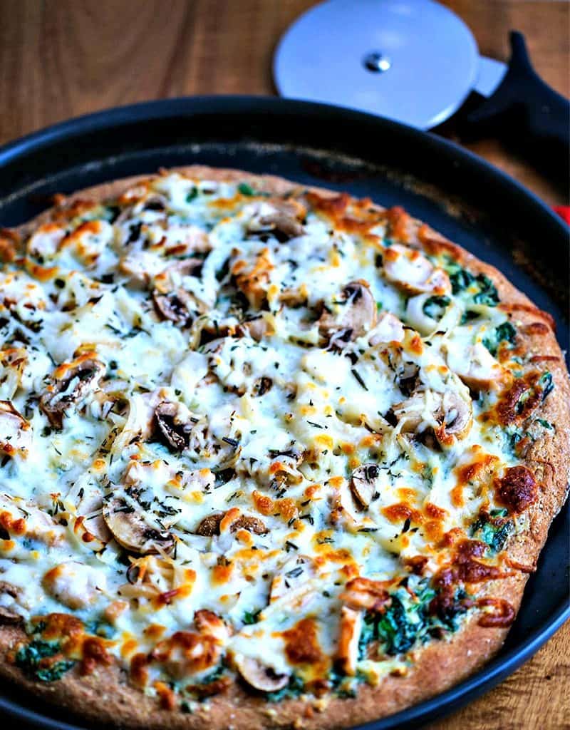 A chicken florentine pizza sitting in a pan on a table
