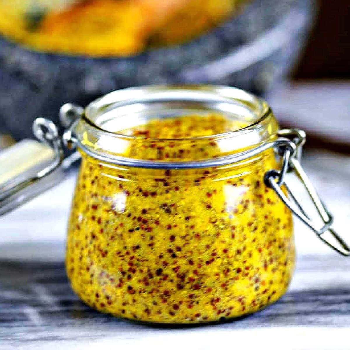 A jar of homemade stoneground mustard on a table.