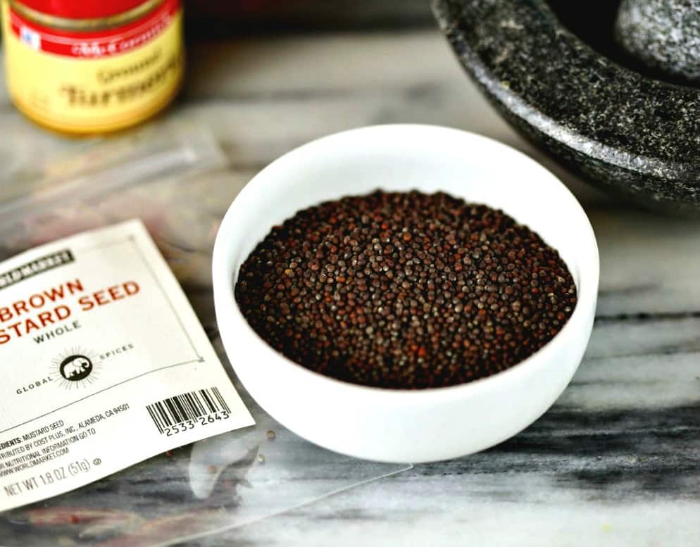 A close up of a bowl of brown mustard seeds