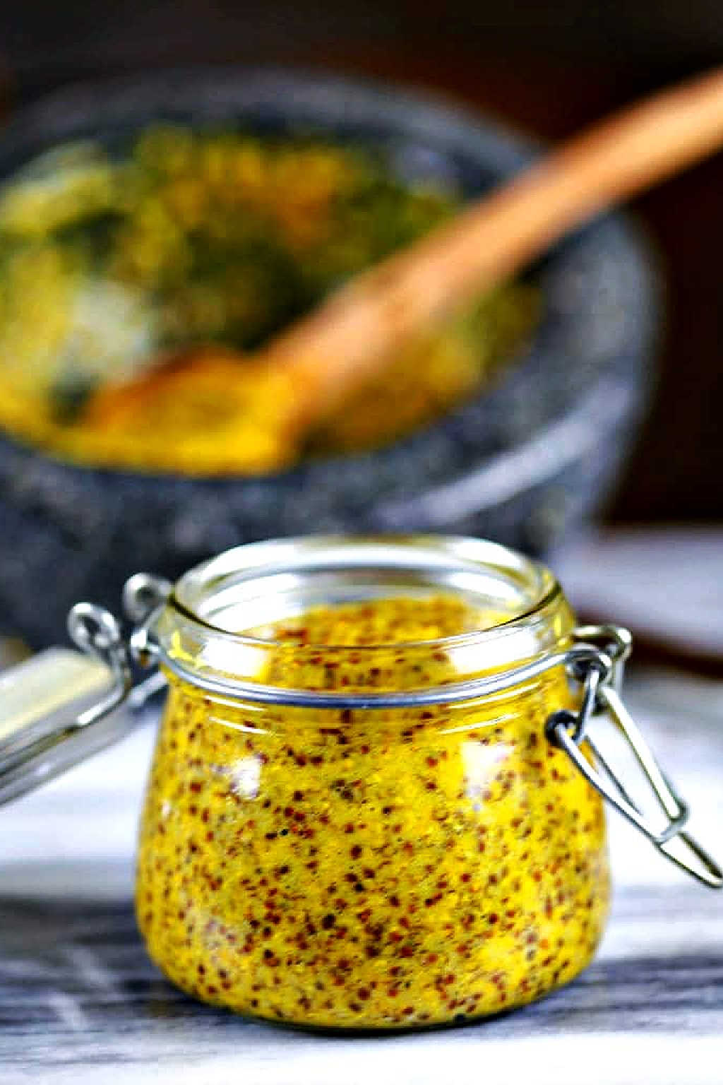 homemade stone-ground mustard in a glass jar on a counter.