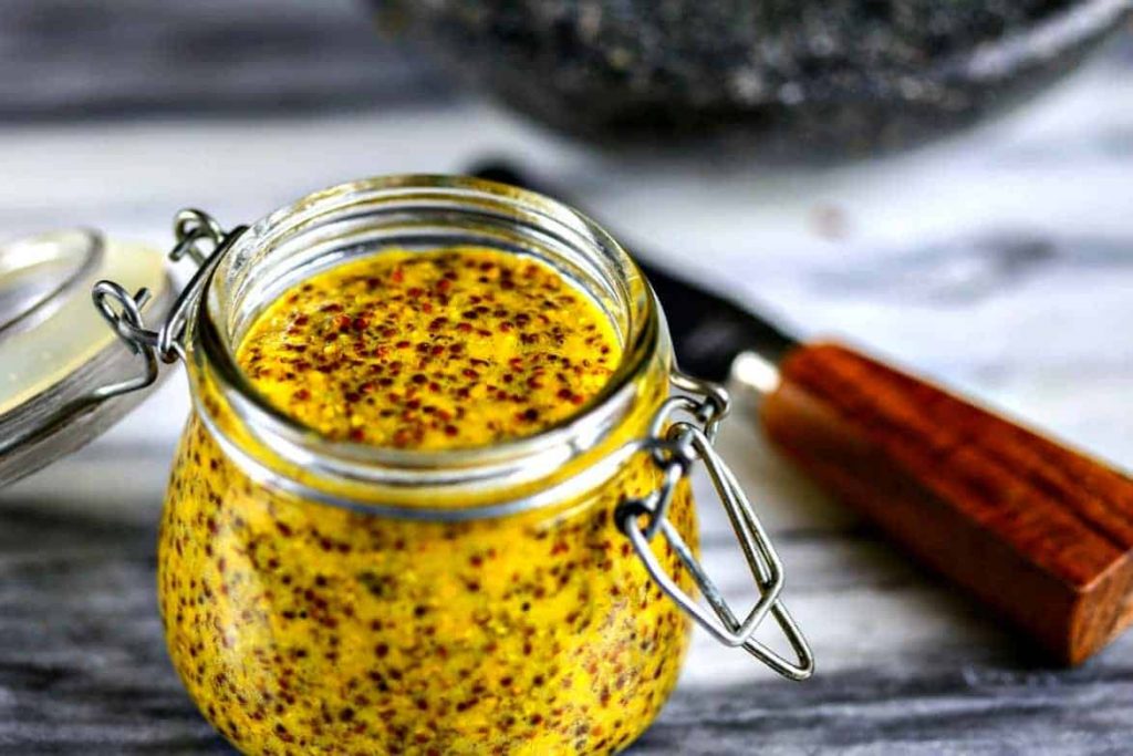 A jar of homemade stone ground mustard sitting on top of a table