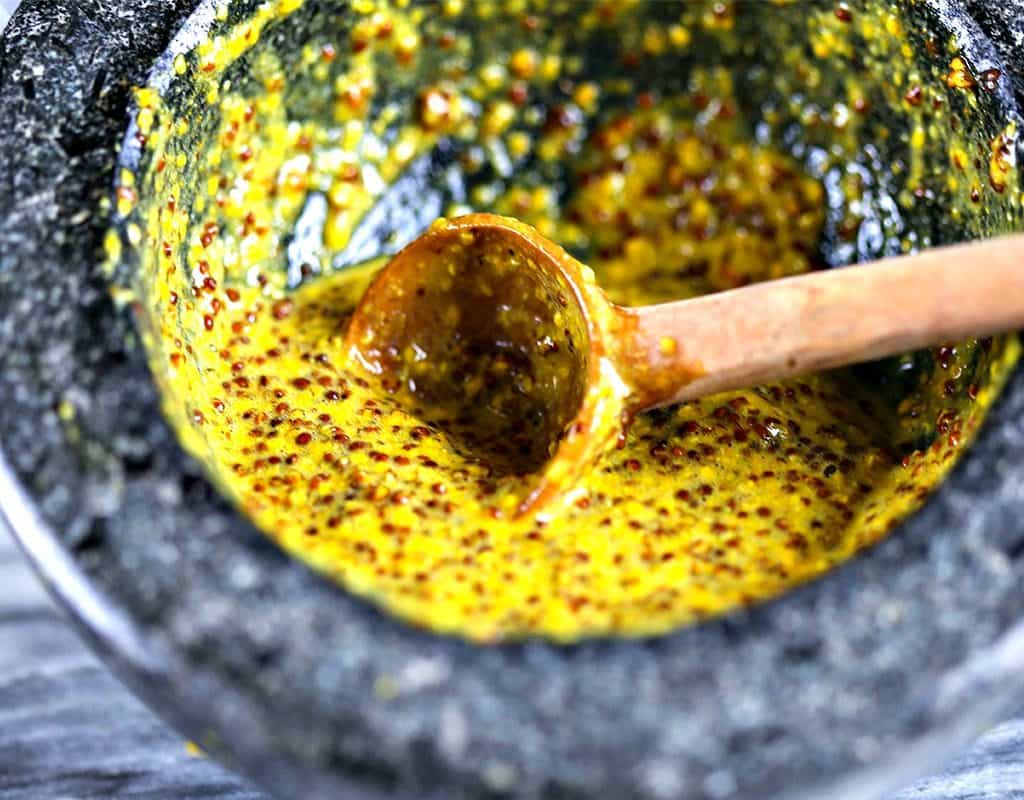 A close up of a bowl of homemade stone ground mustard