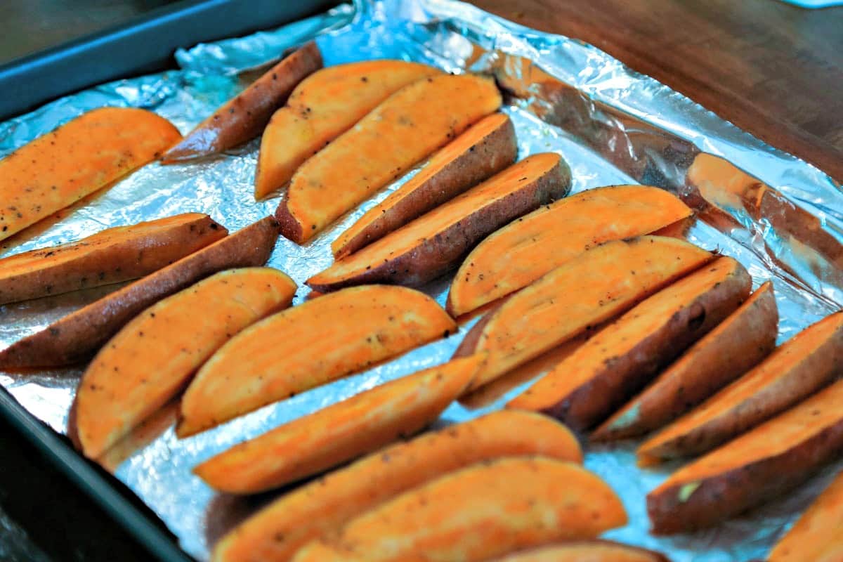 Sweet potato wedges on an aluminum foil lined baking sheet