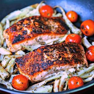 A skillet of Mediterranean Salmon on top of fennel and tomatoes