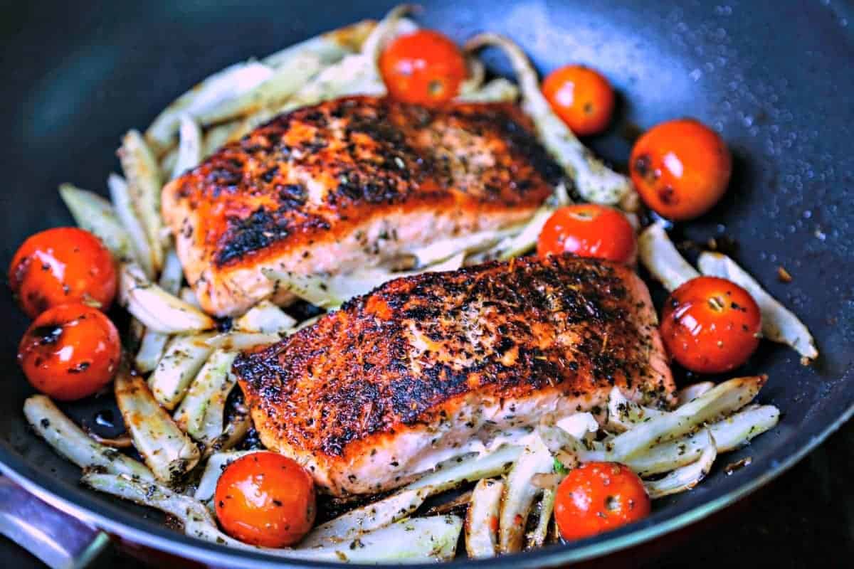A skillet of Mediterranean Salmon on top of fennel and tomatoes