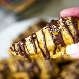 hand holding a chocolate drizzled scone