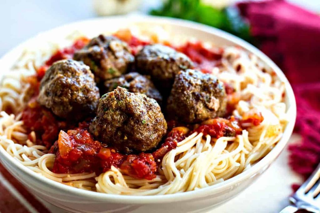 A dish is filled with food, with spaghetti and meatballs