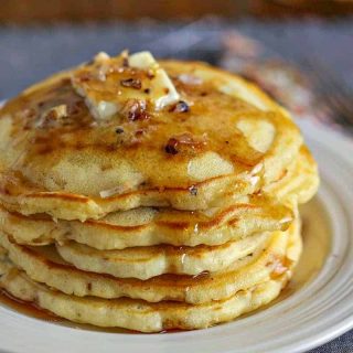 Coconut Pecan Pancakes with butter and maple syrup on white plate