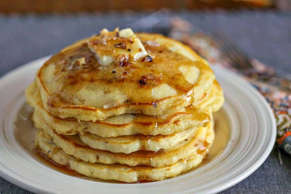 Coconut Pecan Pancakes with butter and maple syrup on white plate