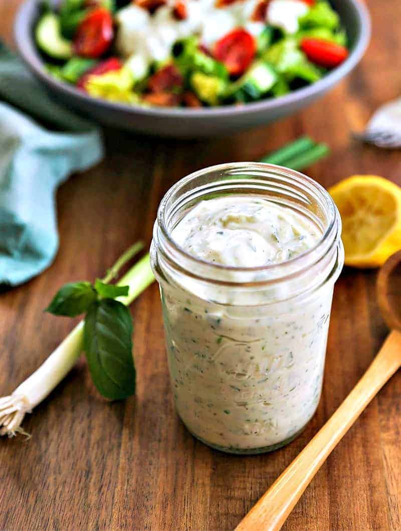 A jar of basil buttermilk dressing sitting on top of a wooden table