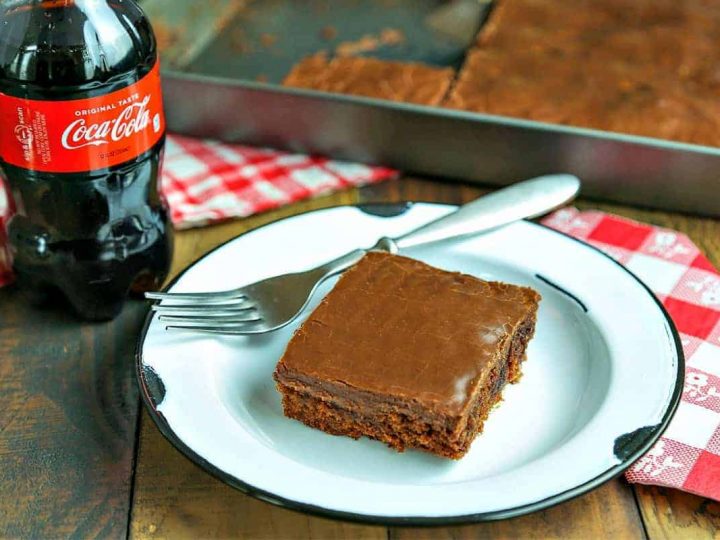 A piece of cake on a plate on a table, with Chocolate Coca-Cola Cake