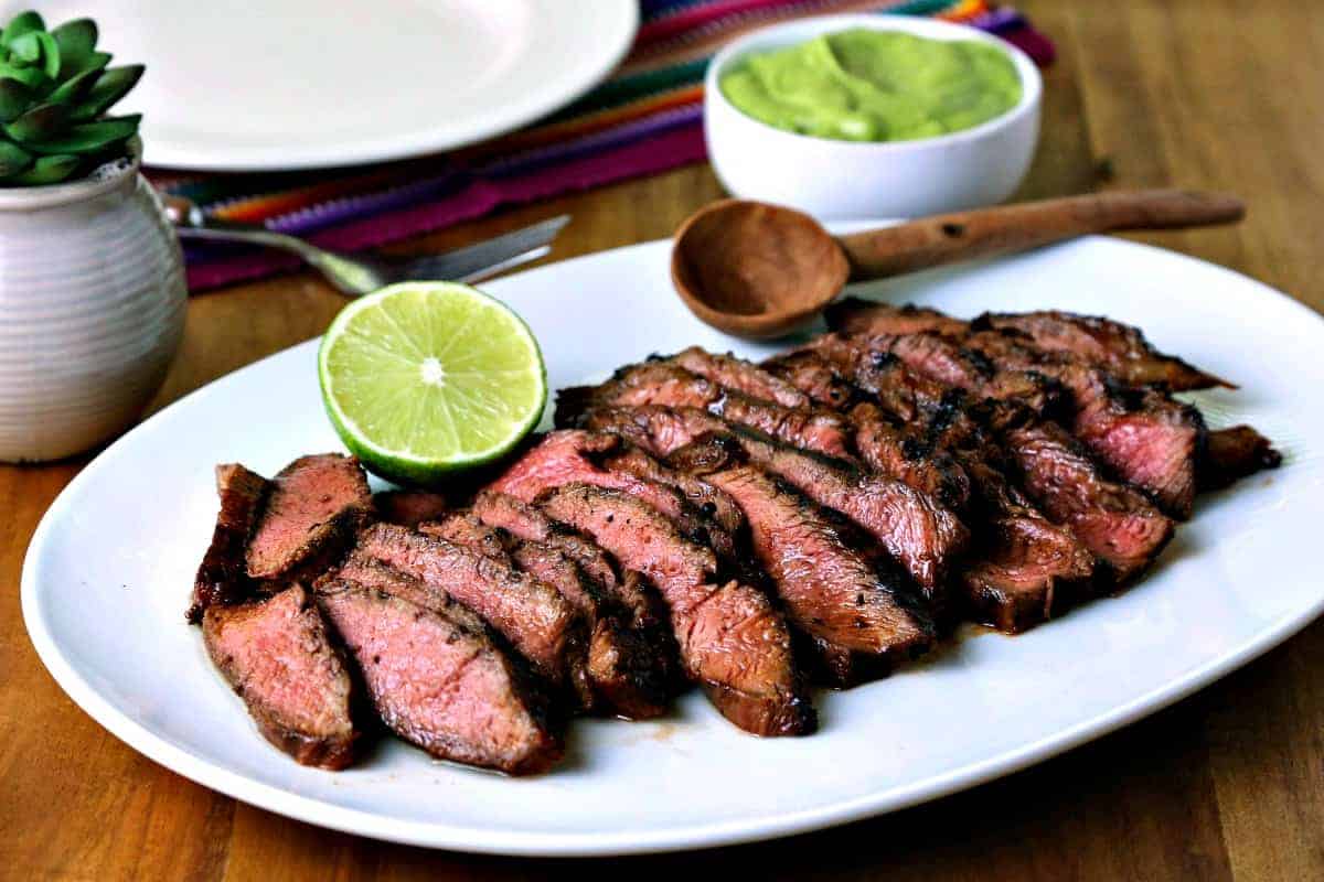 A plate of food on a table, with sliced grilled steak for fajitas