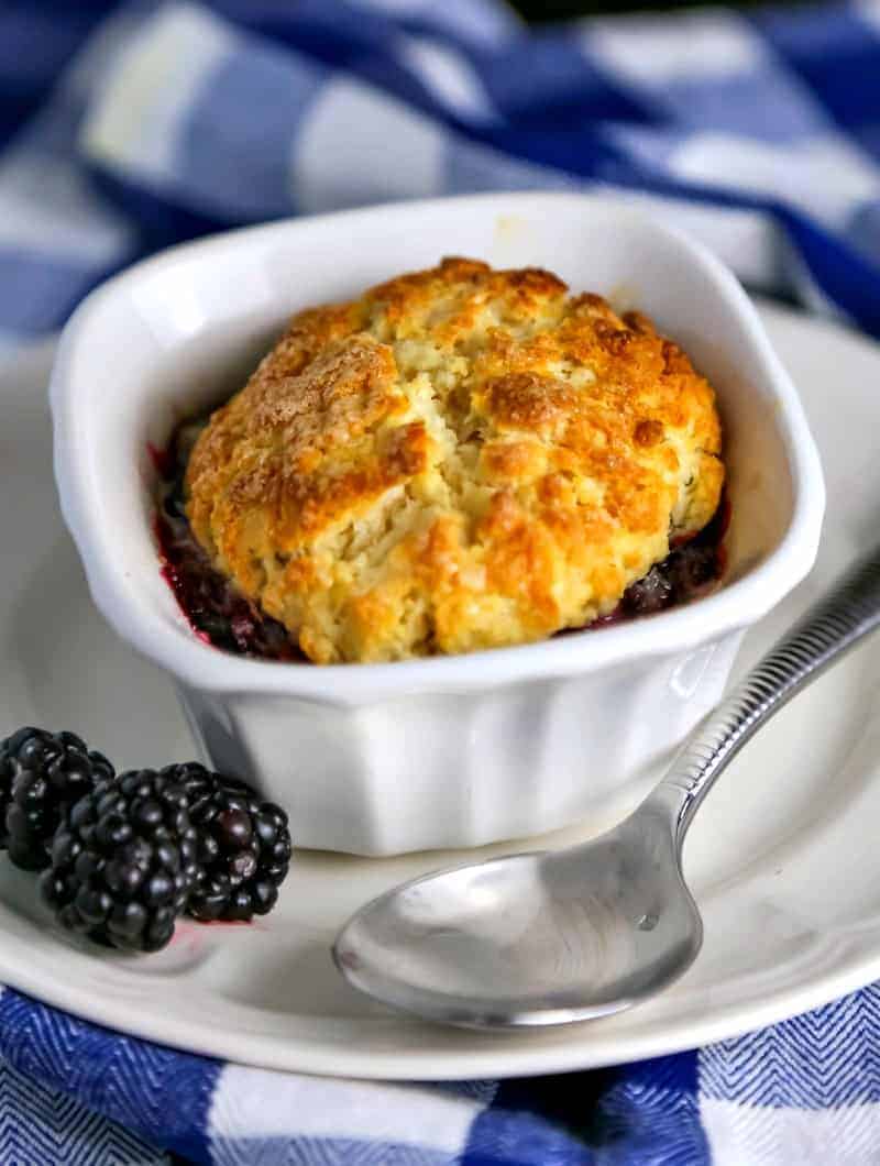 Mini Blackberry Cobbler in a ramekin on a plate with blackberries