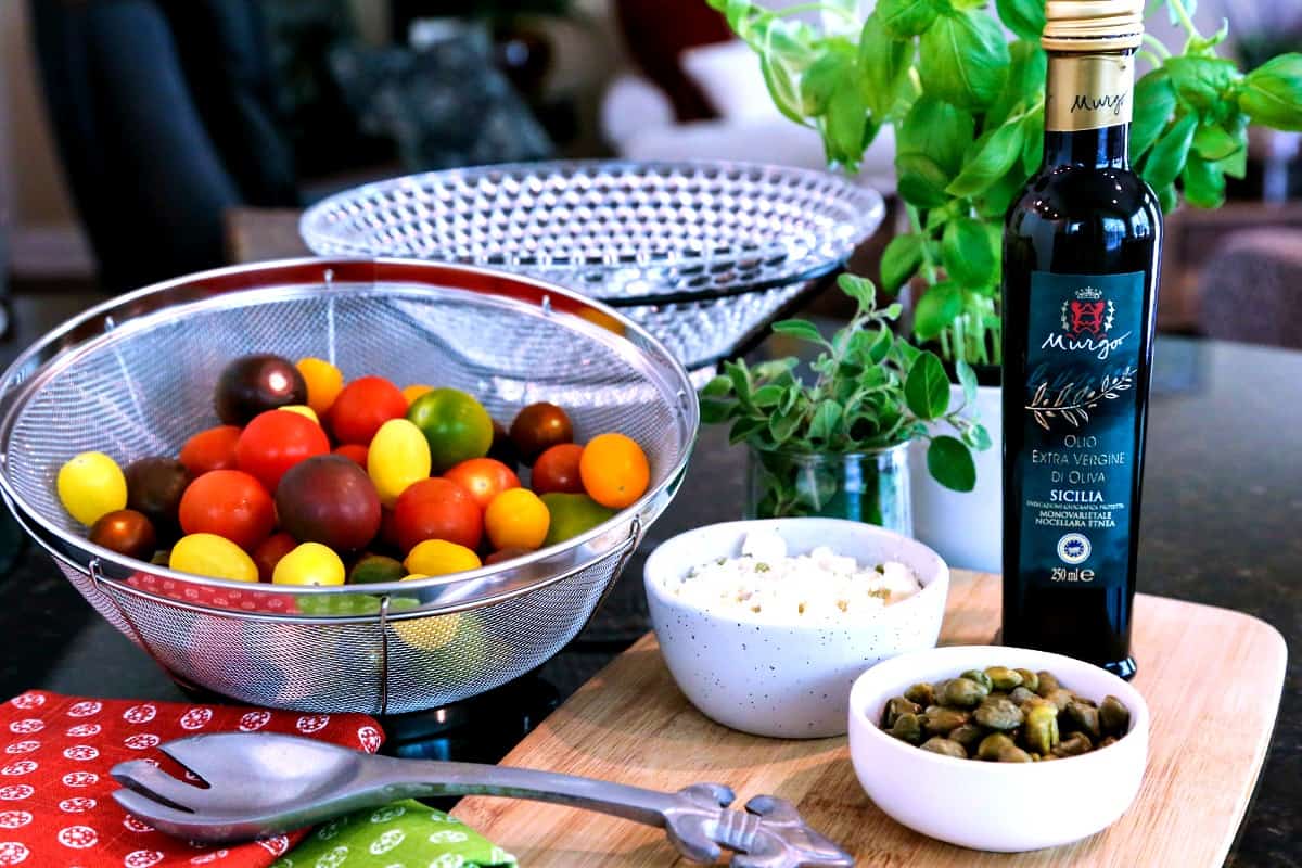 A bottle of balsamic vinegar and a colander of tomatoes