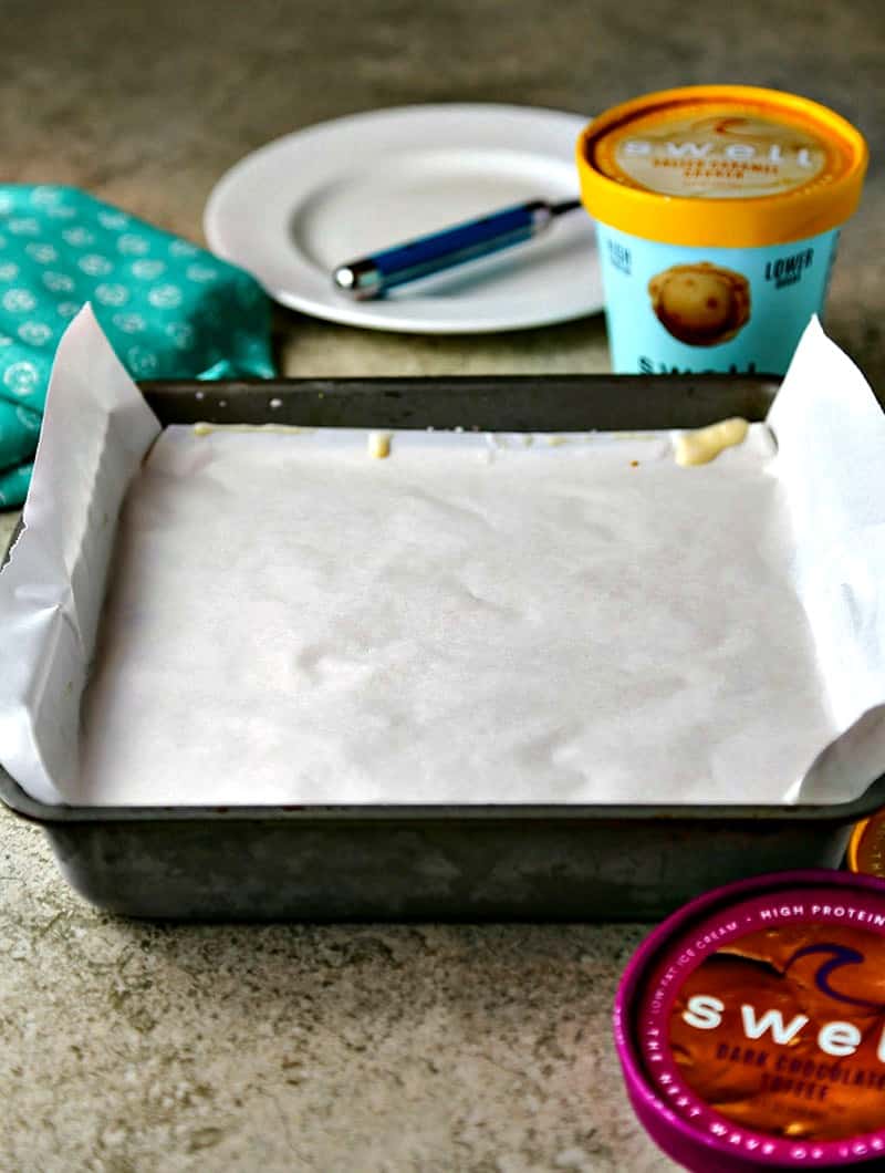 A cake plate with ice cream cake covered with parchment paper