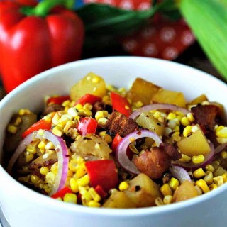 A bowl of food on a plate, with warm corn chowder salad