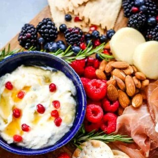 A cheese board with fruit, nuts, and Ricotta