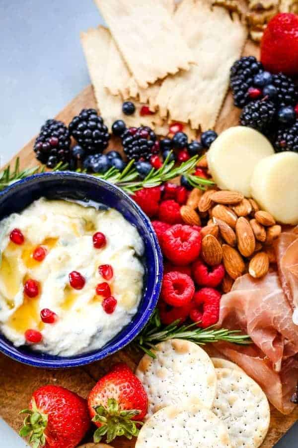 A cheese board with fruit, nuts, and Ricotta