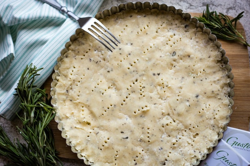 A close up of a plate of a fork pricking a shortbread crust