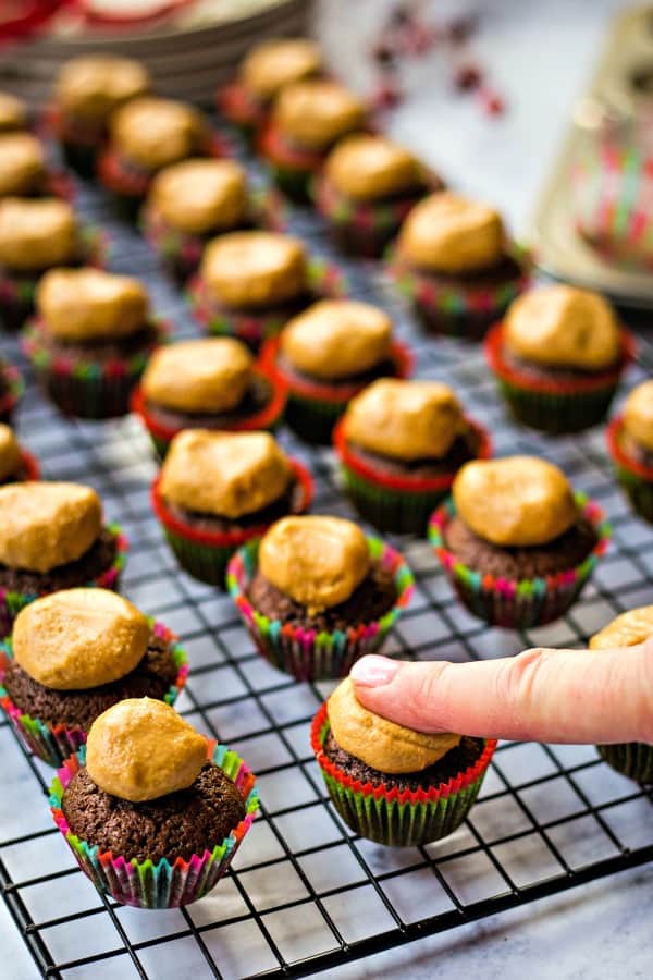 Pressing peanut butter balls onto bite-size brownies in paper cups