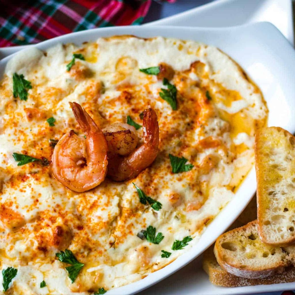 hot cheesy dip with shrimp and baguette slices on a platter