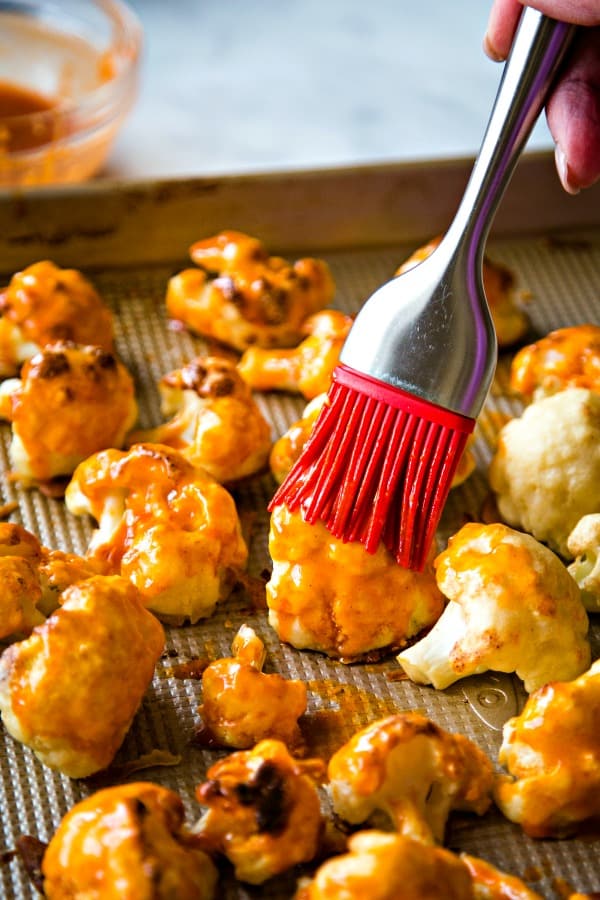 Brushing buffalo sauce onto cauliflower