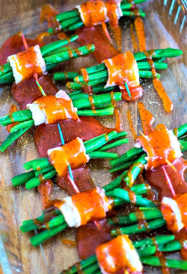 green beans wrapped in bacon with toothpicks in baking dish