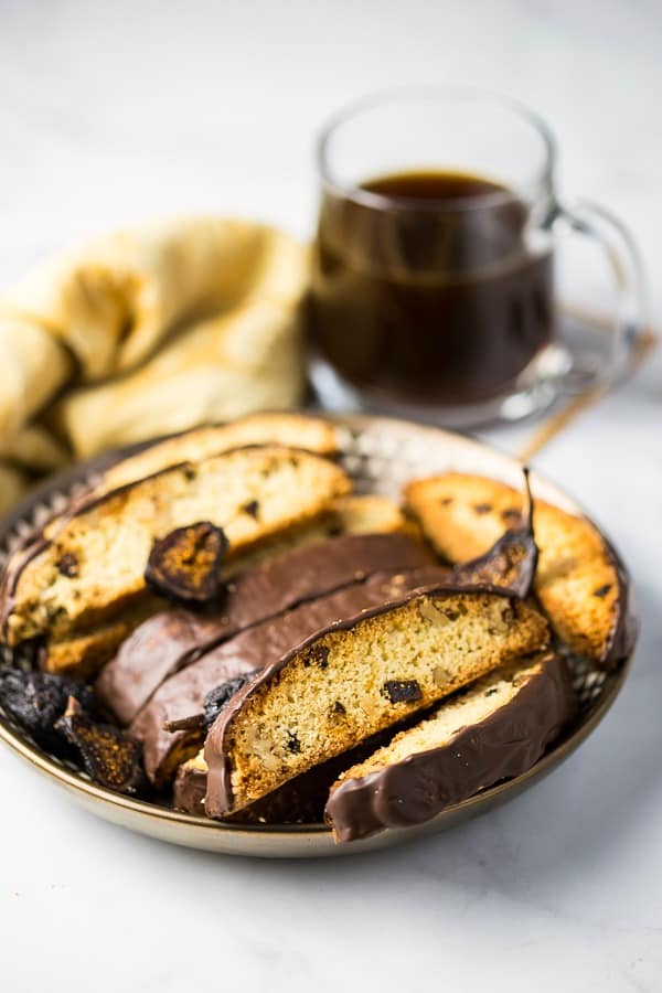 Fig and Walnut Biscotti with Dark Chocolate on gold plate with cup of coffee