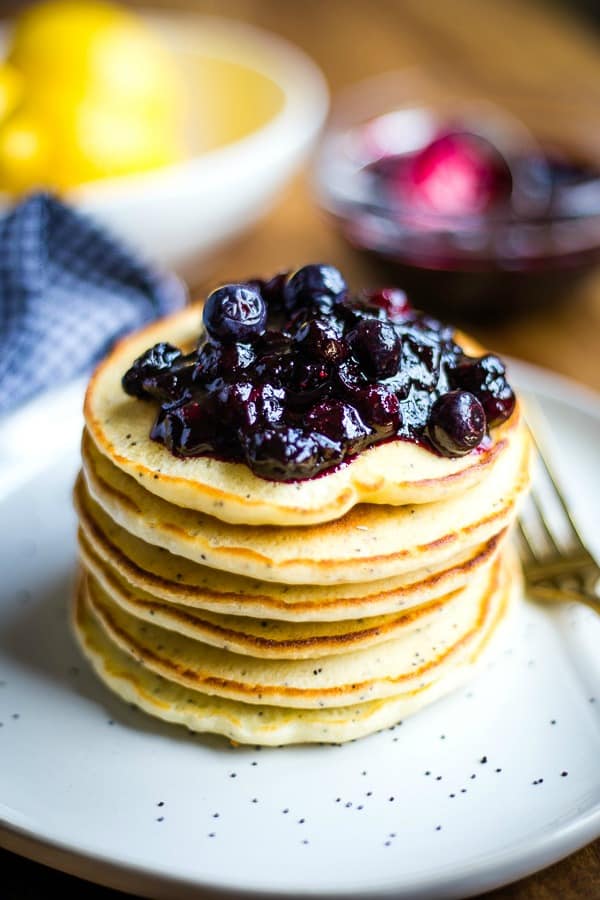 Stack of Lemon Poppy Seed Pancakes with blueberry compote on white plate