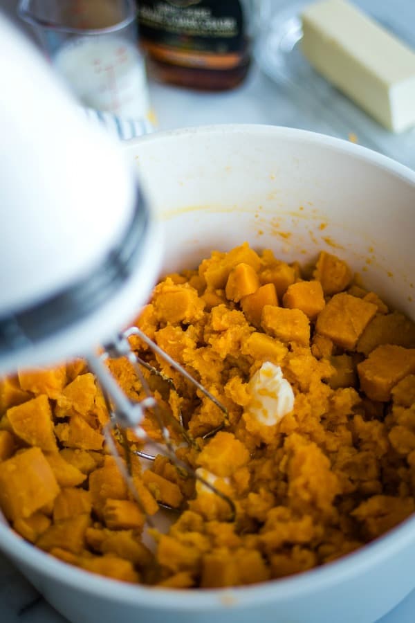 Mashed sweet potatoes in bowl with mixer