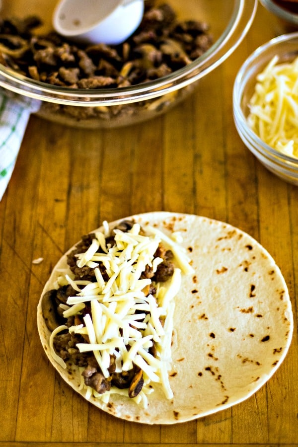 A tortilla on a wooden table, with Sausage and cheese