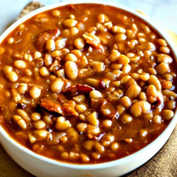 Smoky Chipotle Baked Beans in a white bowl with gold spoon