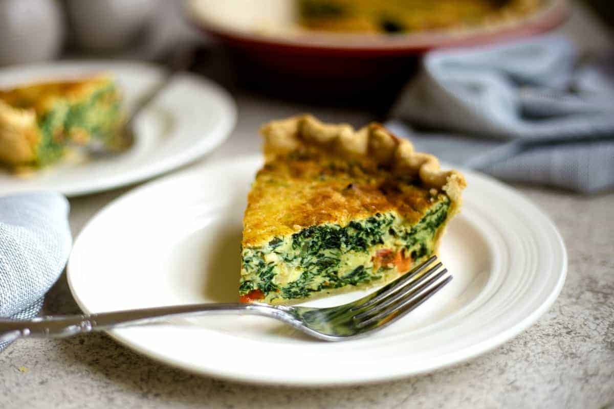 slice of spinach quiche on a white plate