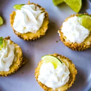 four mini key lime pies on a gray plate with lime garnish
