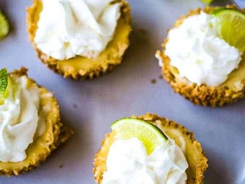 four mini key lime pies on a gray plate with lime garnish