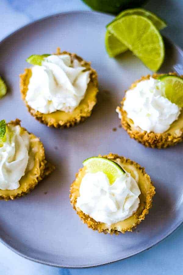 four mini key lime pies on a gray plate with lime garnish