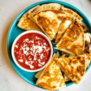 Sausage Pizza Quesadillas on a plate with a bowl of marinara sauce for dipping.