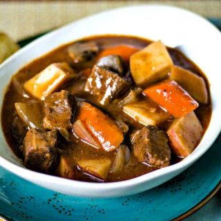 beef stew in a white bowl on a blue plate